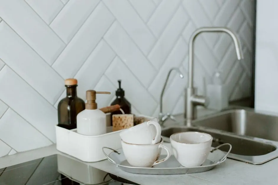 A simple and clean kitchen counter setup featuring tea cups and soap dispensers.
