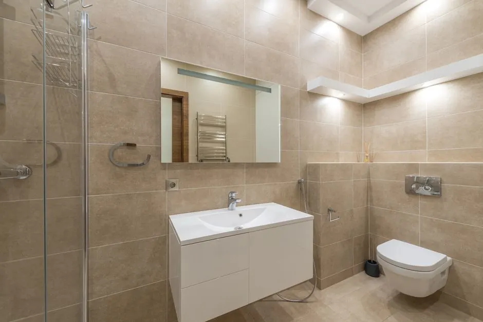 Elegant bathroom with modern fixtures and beige tiles.
